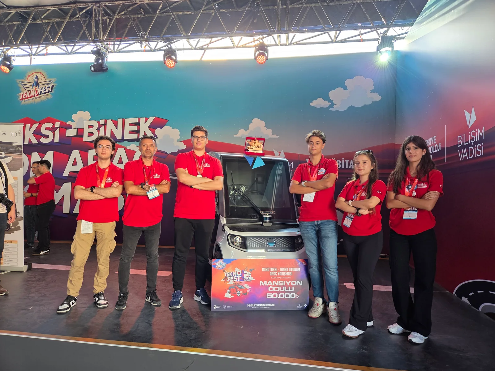 TEKNOFEST team beside an autonomous vehicle at the event stand
